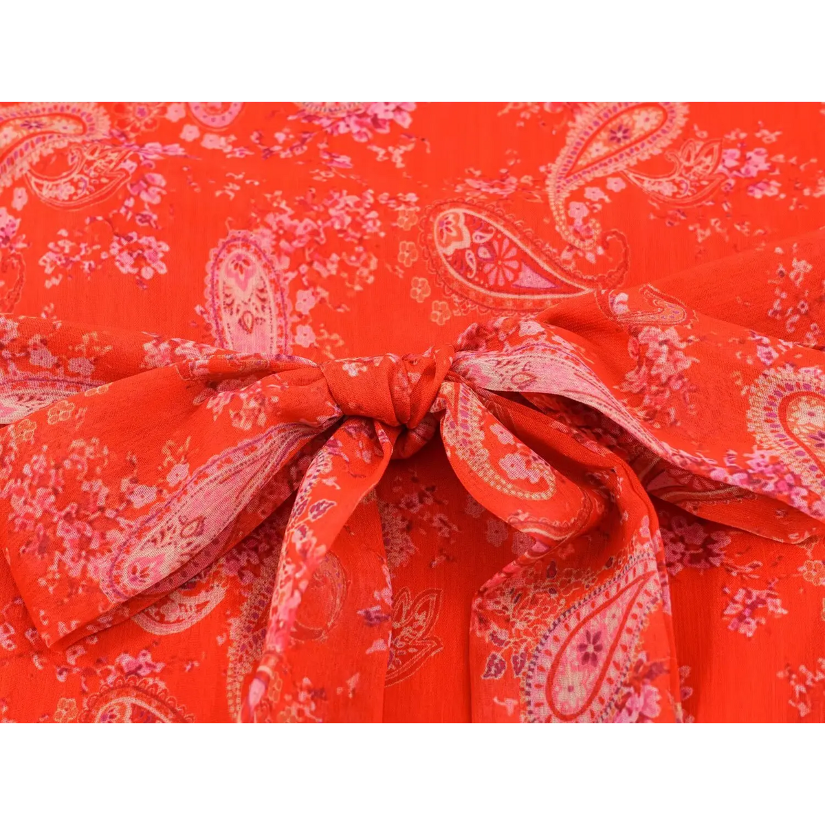 Close-up of waist bow tie on paisley print maxi dress, red base fabric with pink paisley and floral print