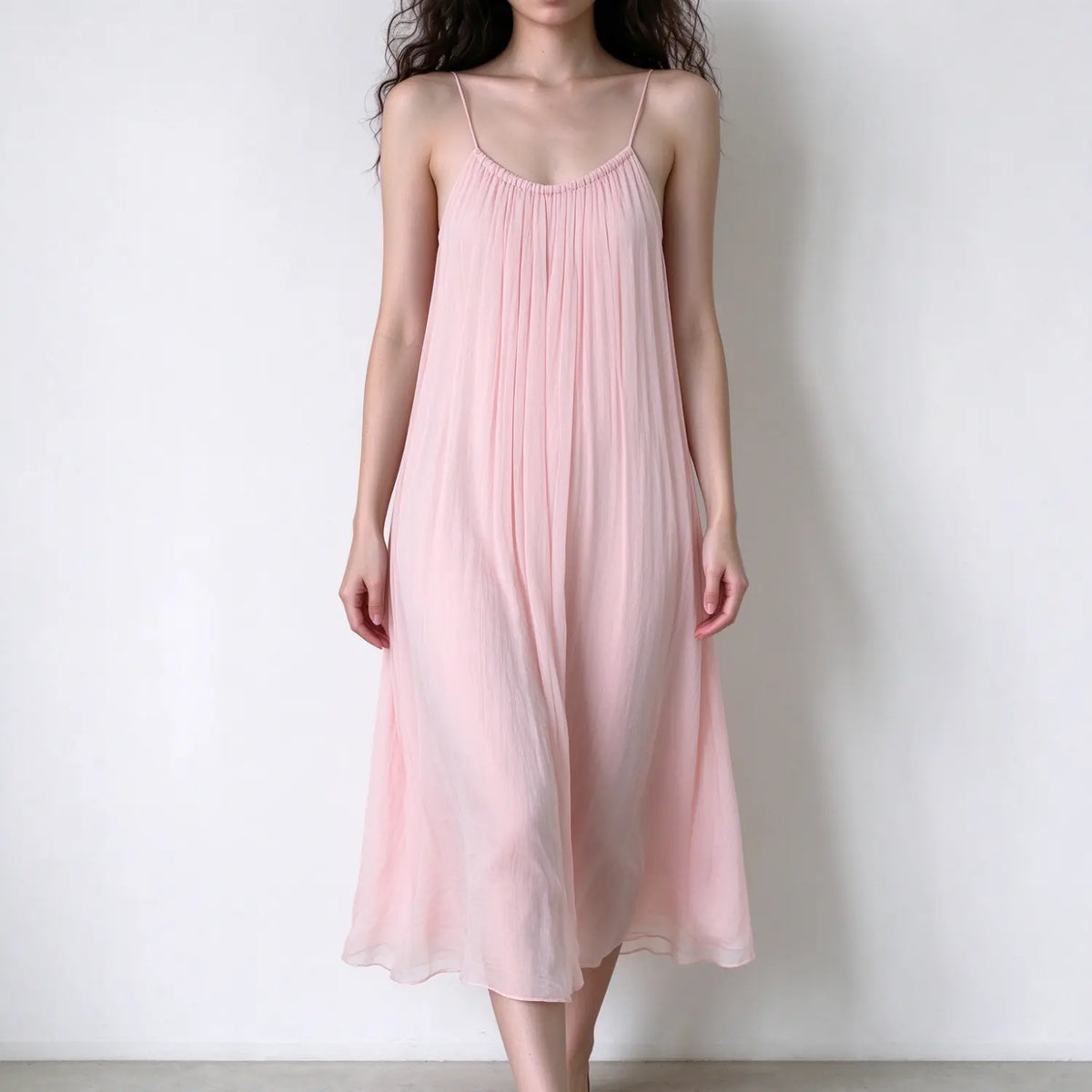 Model wearing pale pink spaghetti strap maxi dress, scoop neck, loose flowy silhouette, lightweight crinkle sheer fabric
