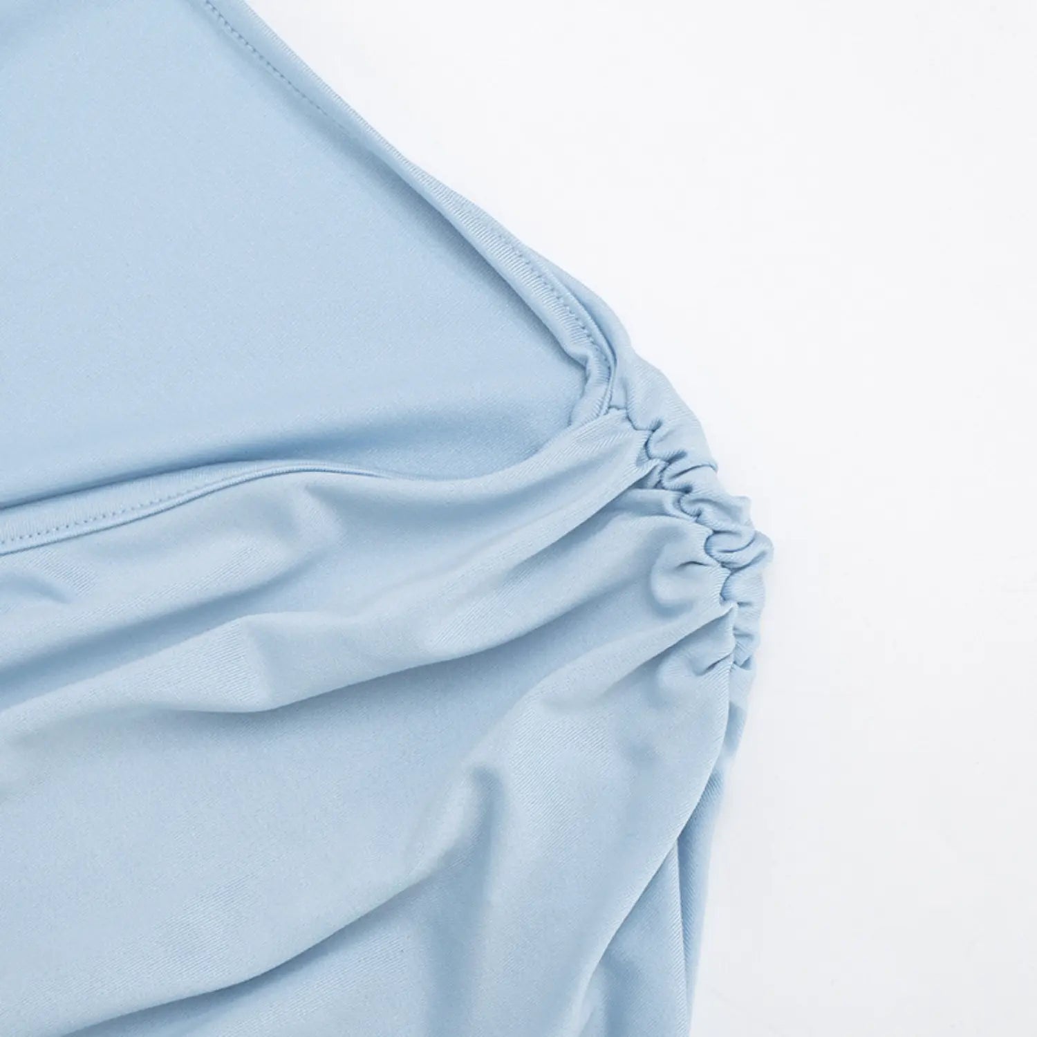 Macro close-up detail of crossover surplice front ruching, soft sky blue smooth stretch knit fabric, tight uniform gathered stitching, clean hidden seam construction, matte wrinkle-resistant textile texture