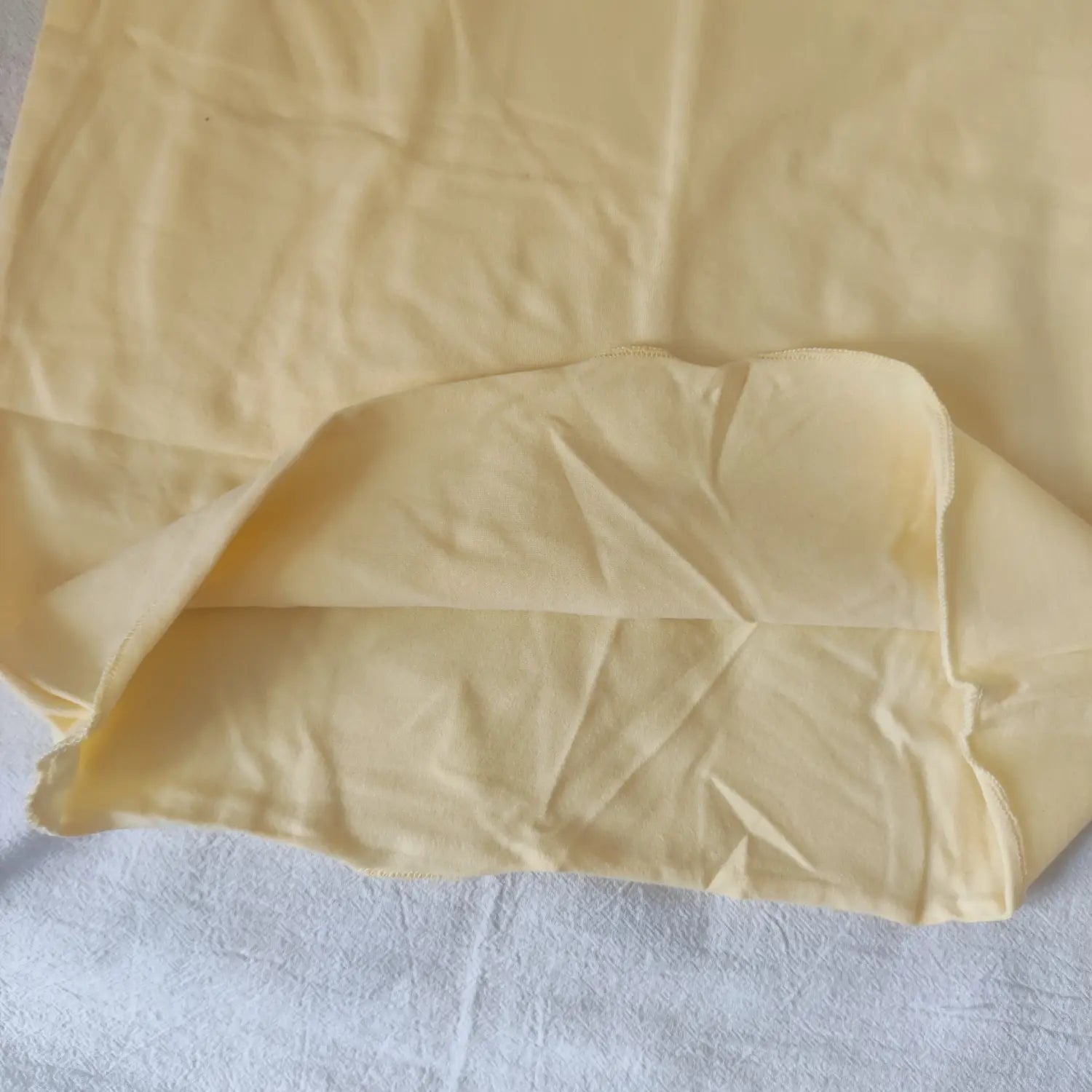 Close-up view of pale yellow cami mini dress, wavy hem fabric detail