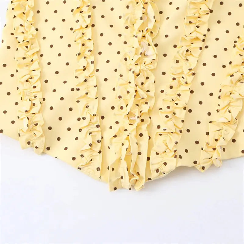 Front flat lay product shot pale yellow cami top, brown polka dot print, self tie spaghetti straps, allover ruffle trim, corset curved hem
