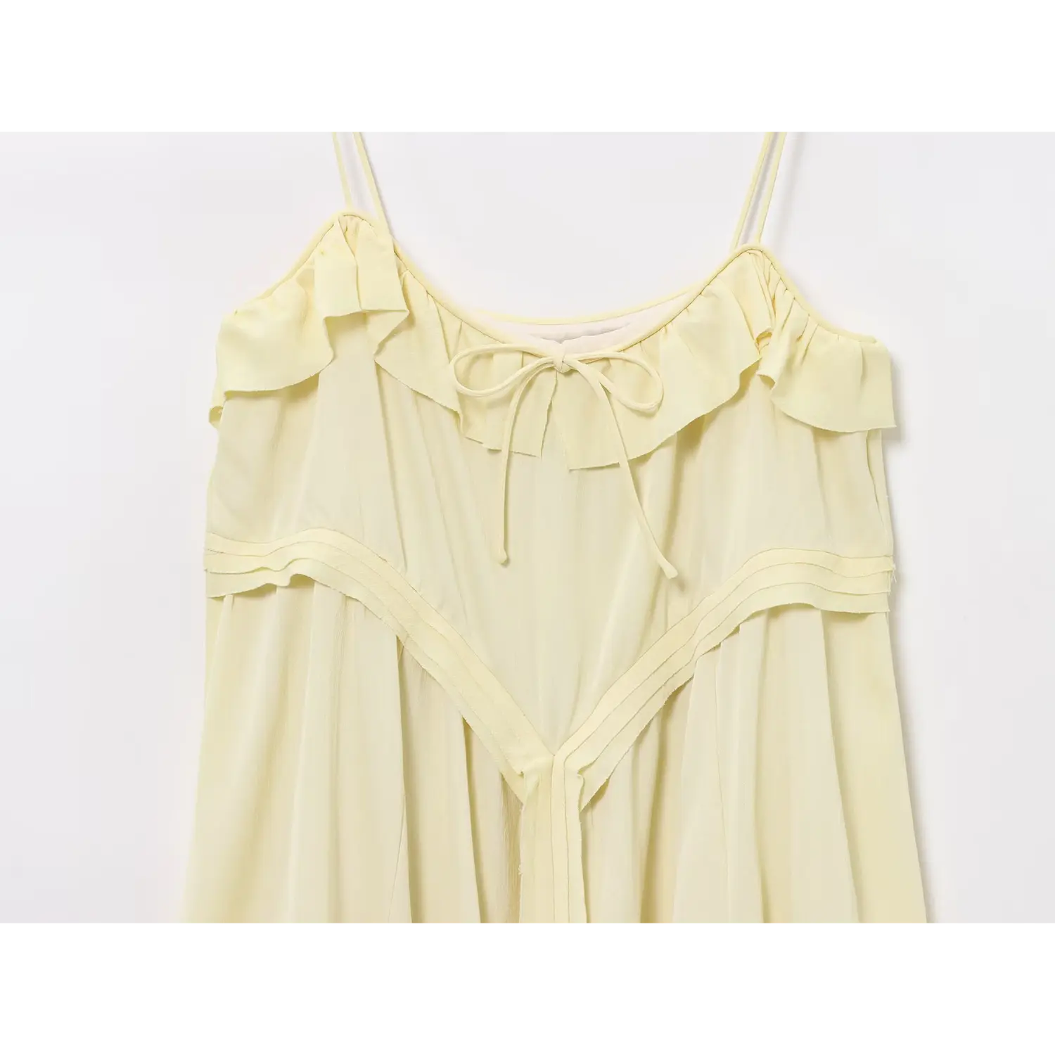 Front detail of pale yellow spaghetti strap dress with ruffle collar and layered v-shaped waist stitching
