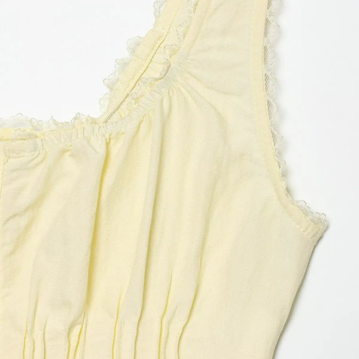 Close-up of the lace-trimmed strap on the pale yellow cami top, showing the scalloped lace edge and gathered neckline