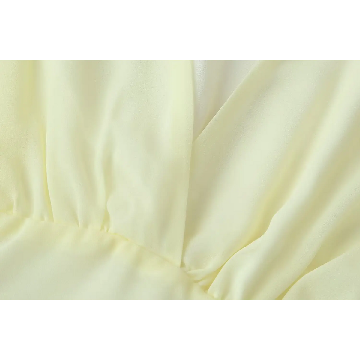 Close view of waist ruffle connection and lightweight chiffon material for pale yellow tiered dress