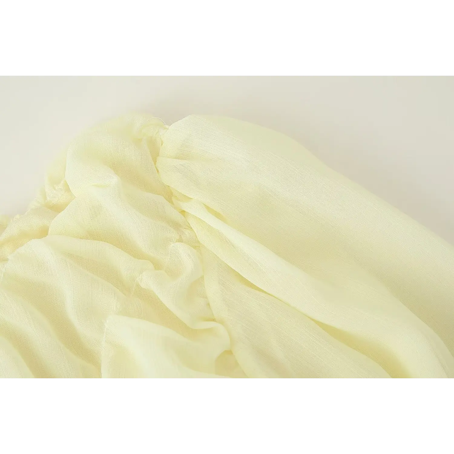 Close-up of pale yellow vertical crinkle chiffon fabric, gathered ruched bust detail, lightweight sheer flowy dress material