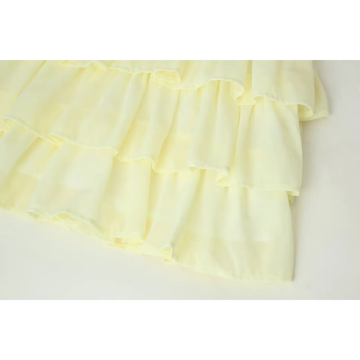 Detail shot of cascading multi-tier ruffle hem, flowy pale yellow chiffon fabric