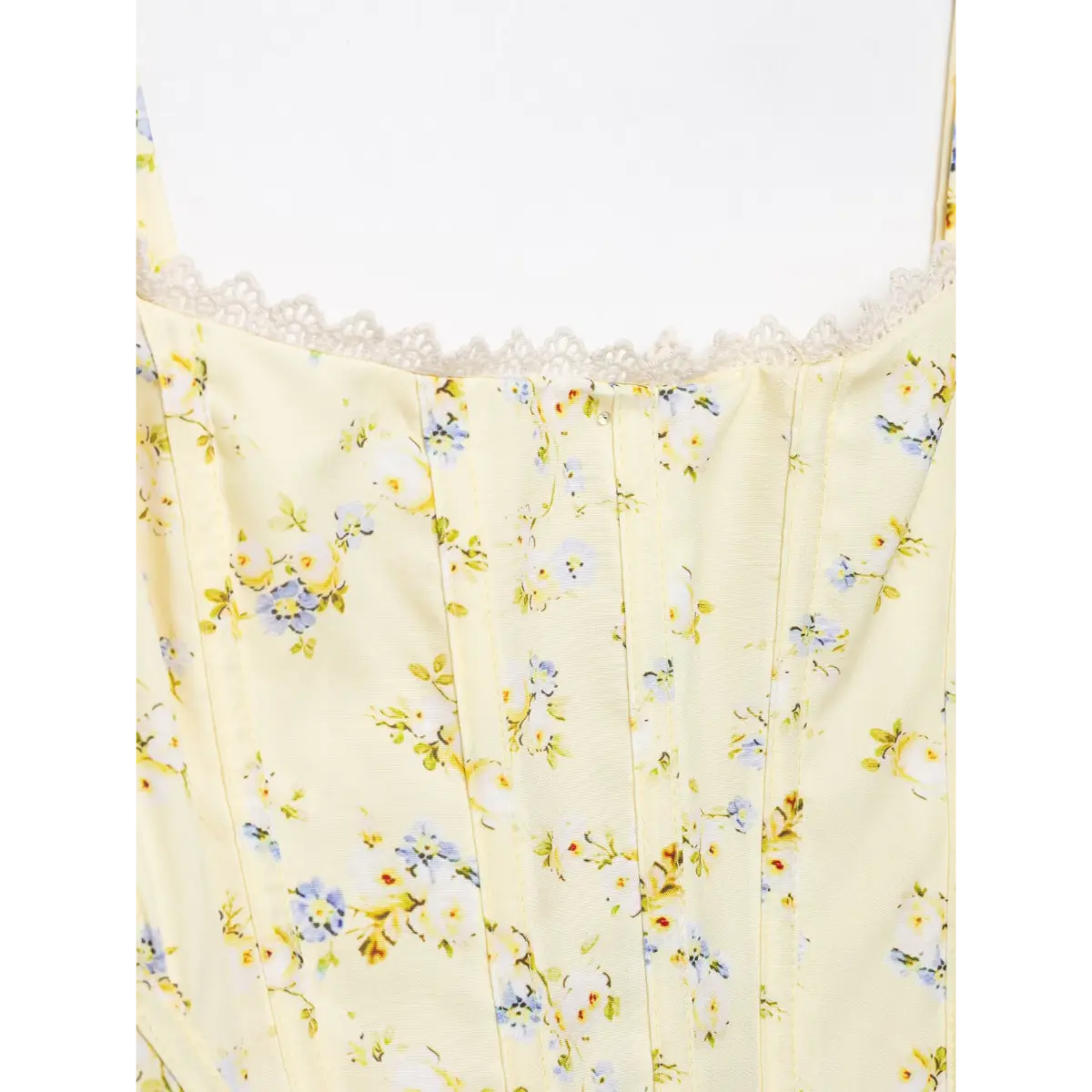 Close-up of front bust area, lace trim and structural boning on pale yellow floral corset top.