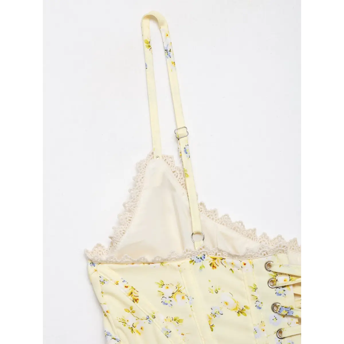 Close-up of adjustable spaghetti strap and lace trim on pale yellow floral corset top.