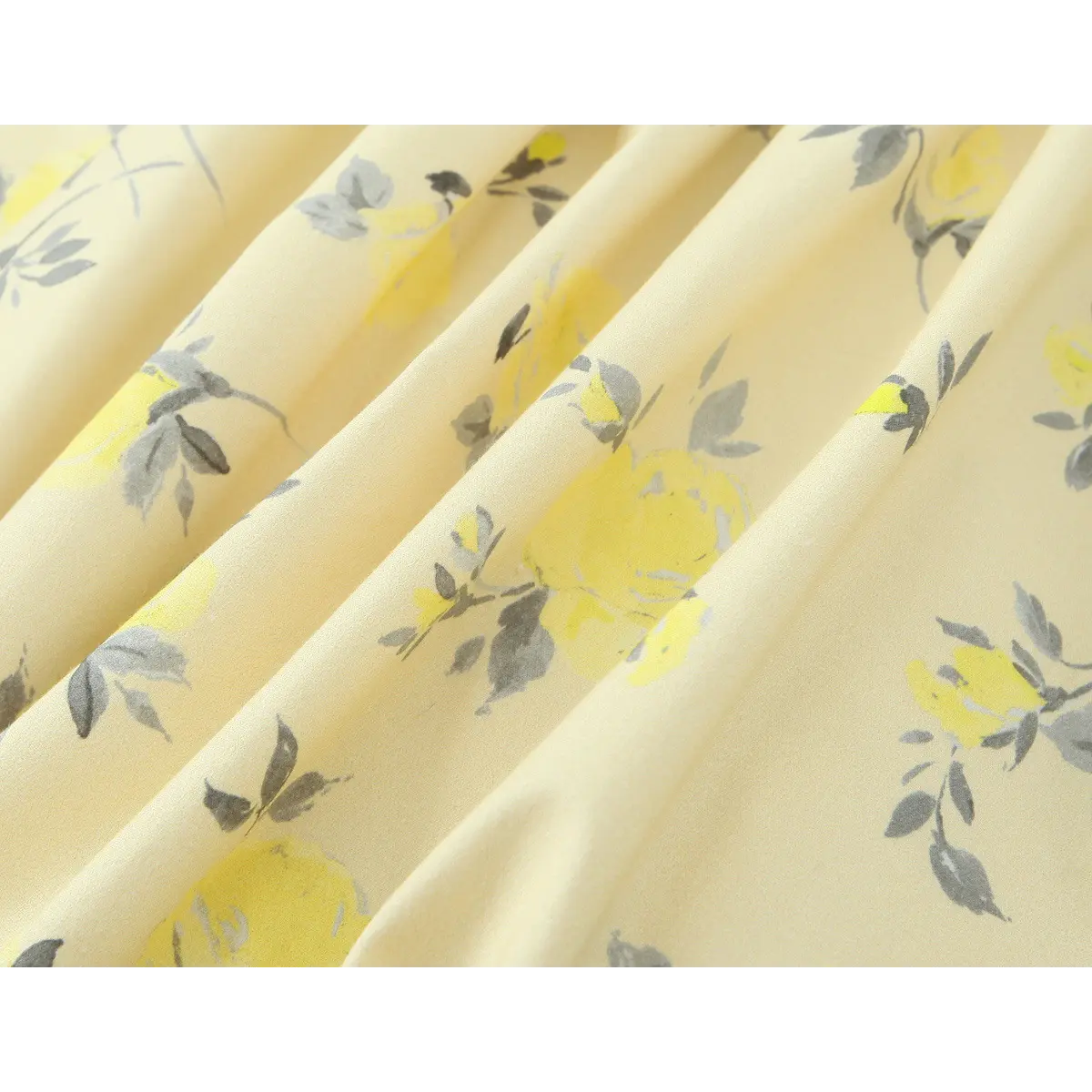 Close-up of the fabric texture and floral print on a pale yellow spaghetti strap dress, showing the soft drape.