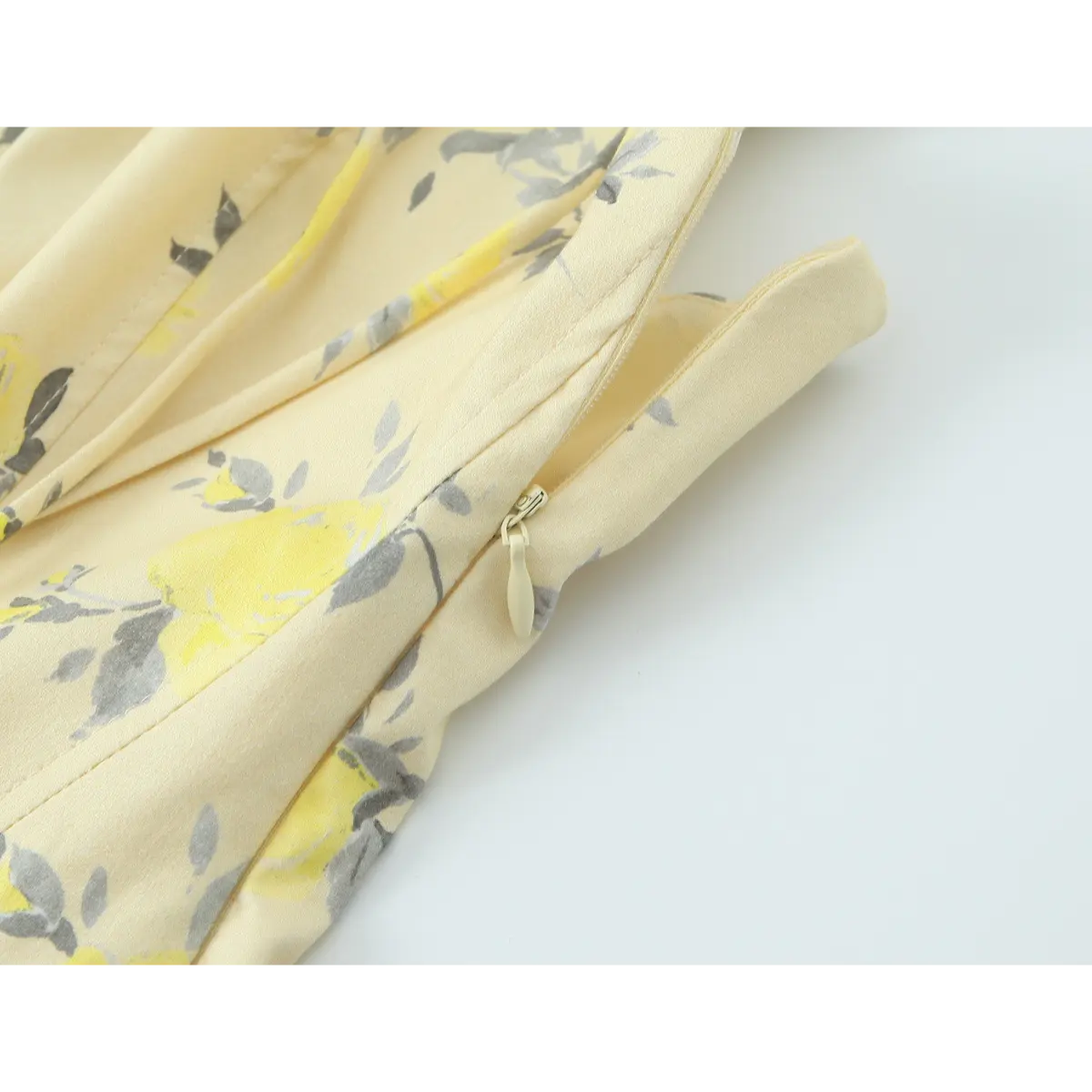 Close-up of the hidden side zipper on a pale yellow floral print spaghetti strap dress.