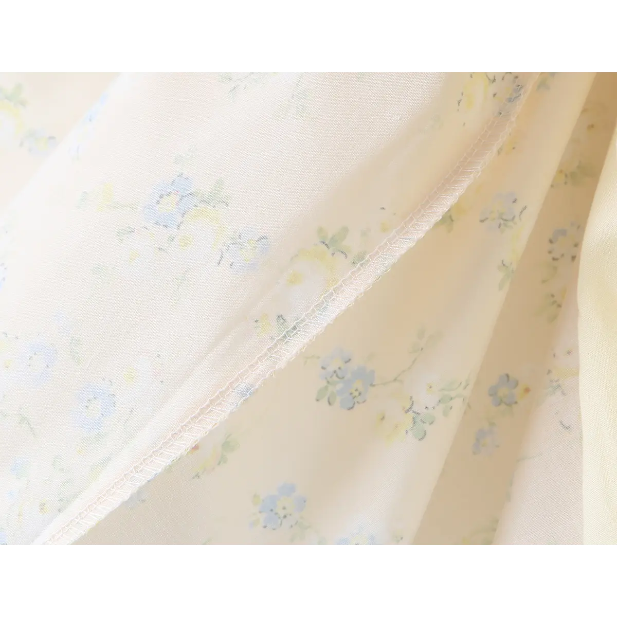 Close-up of the overlock stitching, showcasing the soft texture of the lightweight floral fabric.
