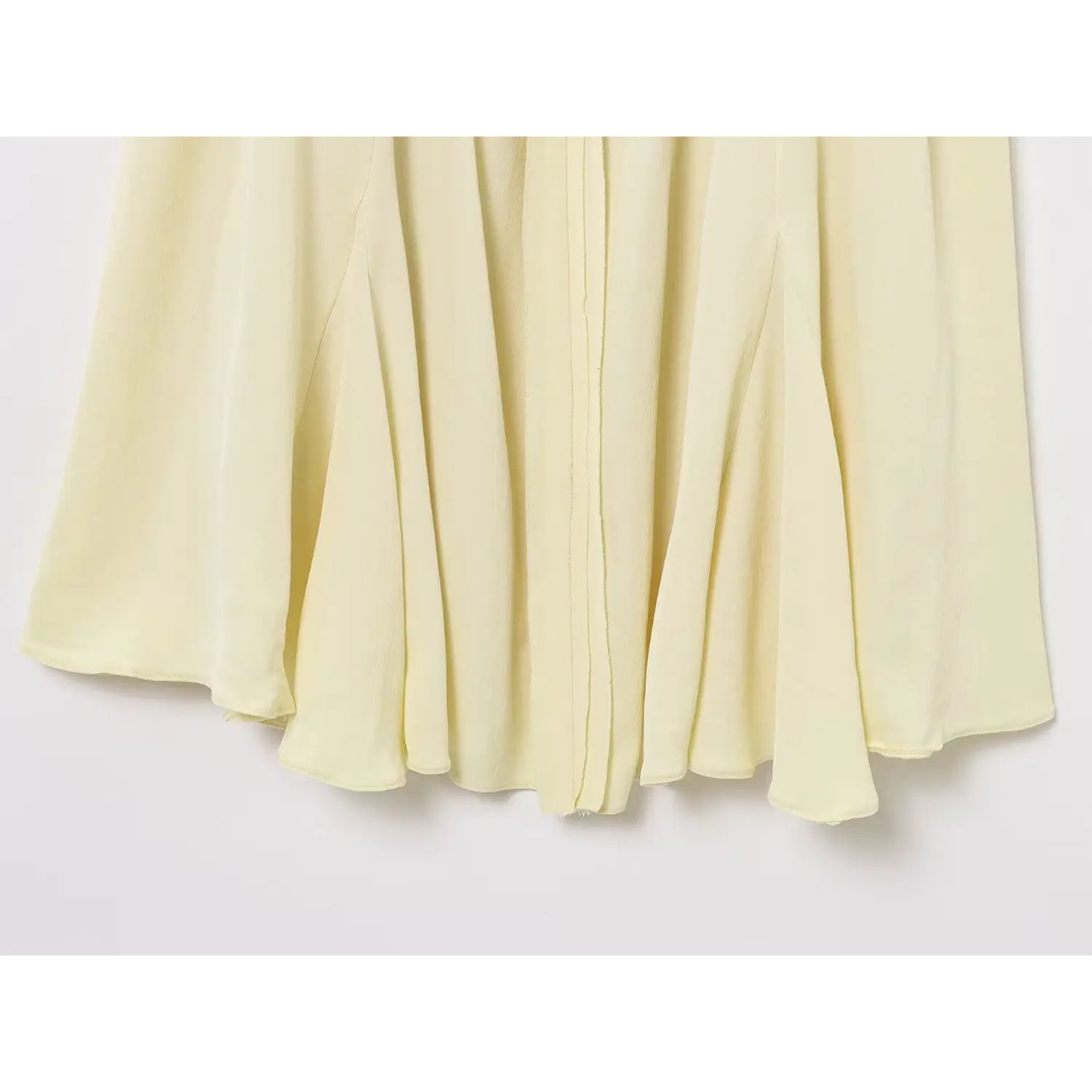 Close-up view of flared flowy skirt hem on pale yellow chiffon spaghetti strap dress
