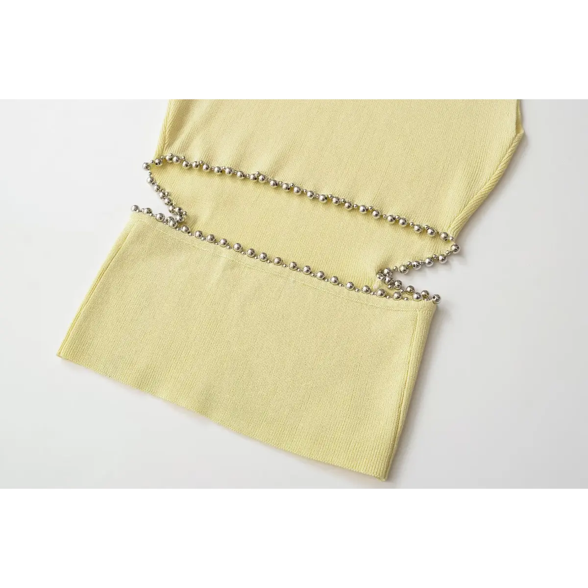 Close detail of silver ball bead edged side cutout on yellow rib knit tank