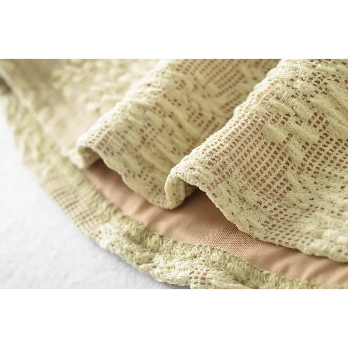 Close-up of the lace hem, showing the contrast between the pale yellow lace exterior and nude lining.
