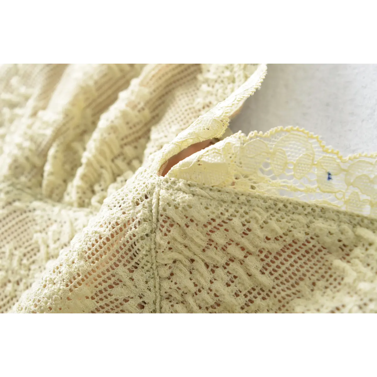 Close-up of the V-neckline, featuring the scalloped lace trim and gathered bust detail.
