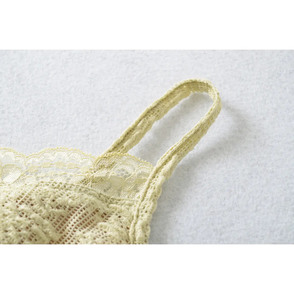 Close-up of the delicate lace-covered adjustable strap on the pale yellow camisole.