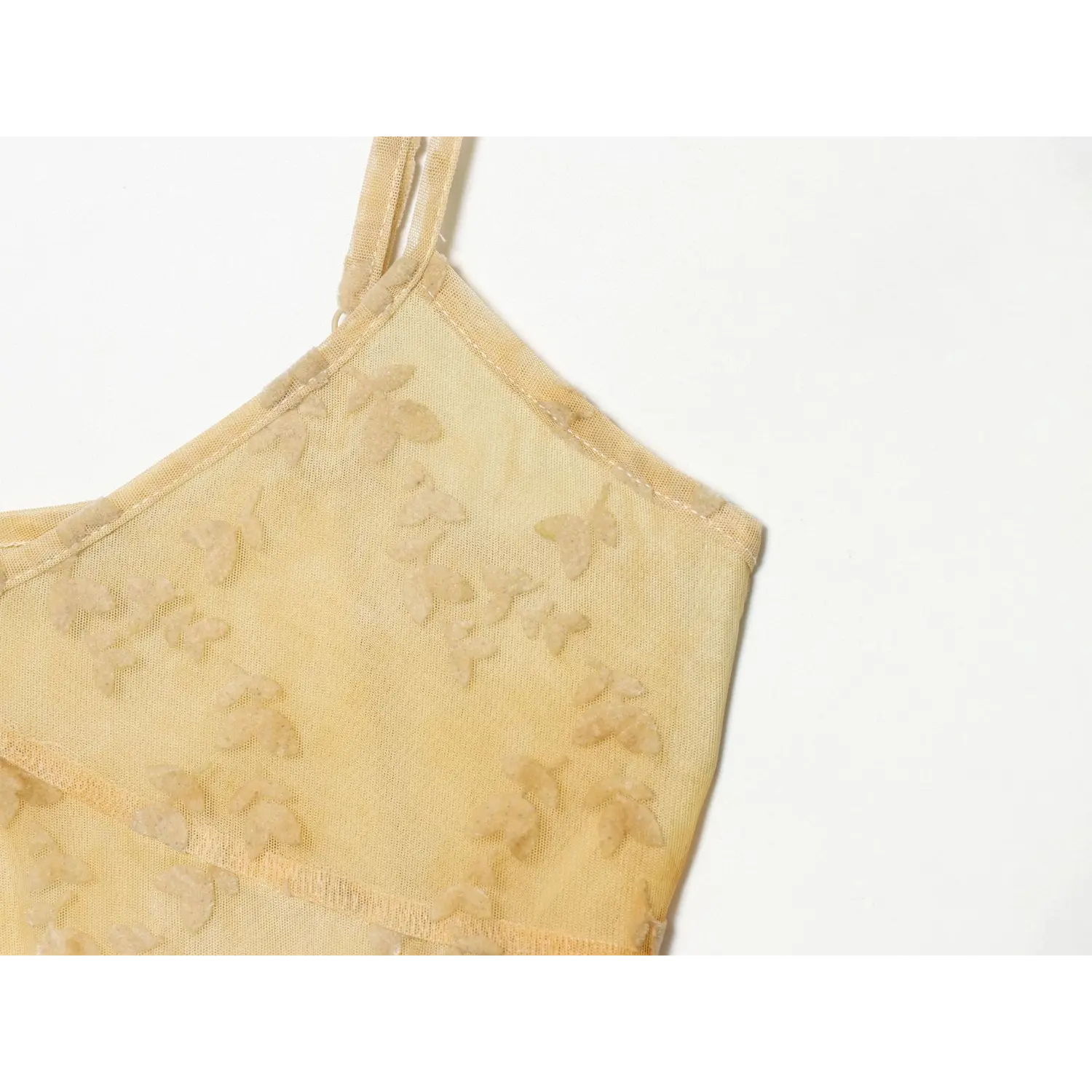 Close‑up fabric detail of pale yellow leaf jacquard mesh maxi dress, textured leaf motif on sheer mesh material