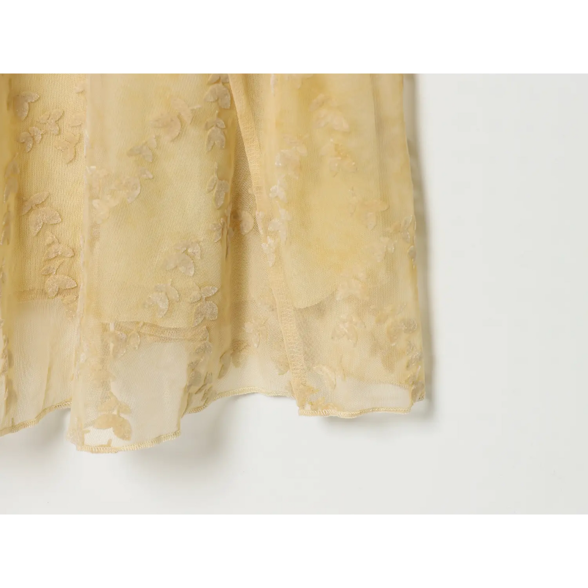 Close‑up hem edge of pale yellow leaf jacquard mesh maxi dress, sheer mesh fabric and fine finished stitching