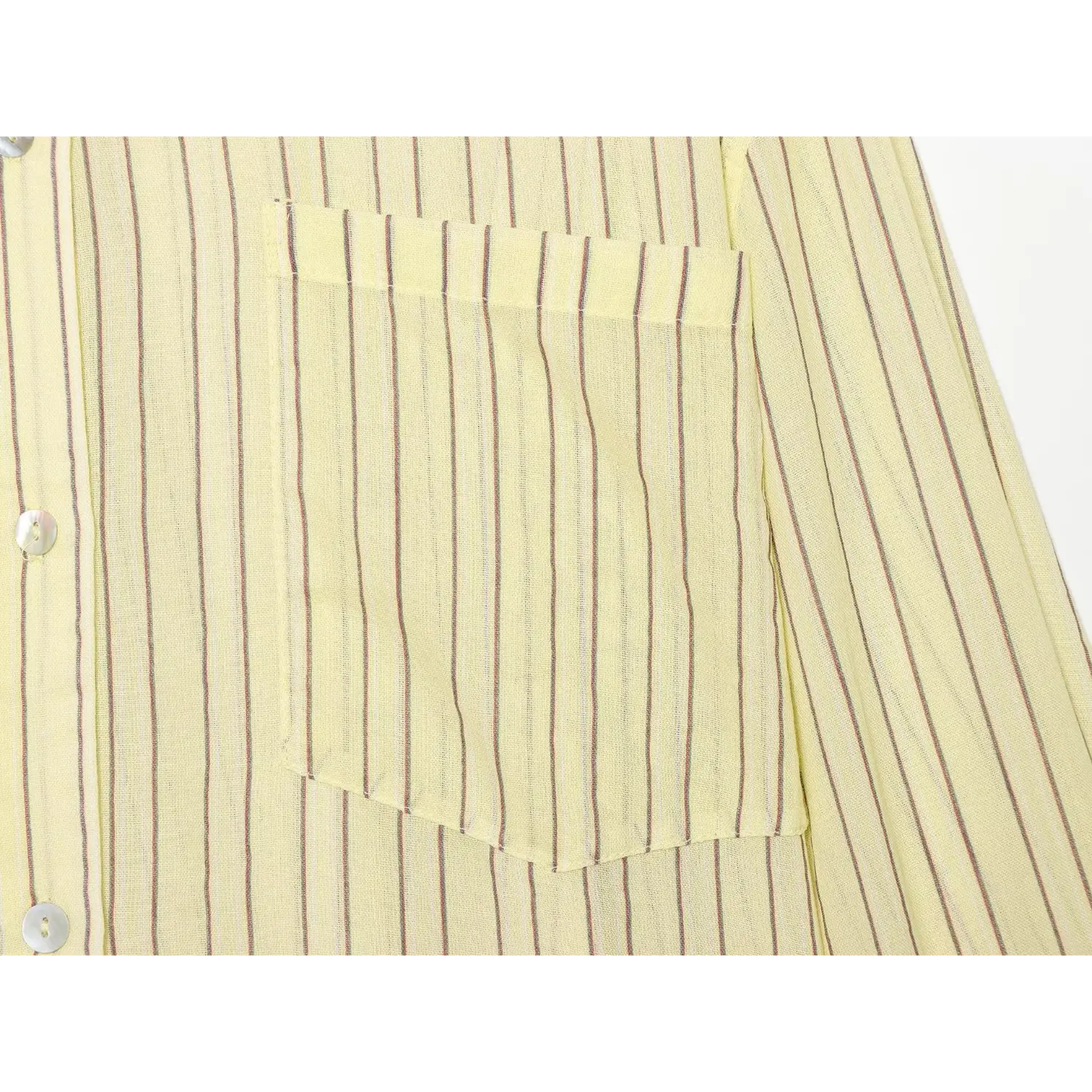 Closeup flat shot of chest patch pocket & shell buttons on pale yellow vertical stripe blouse