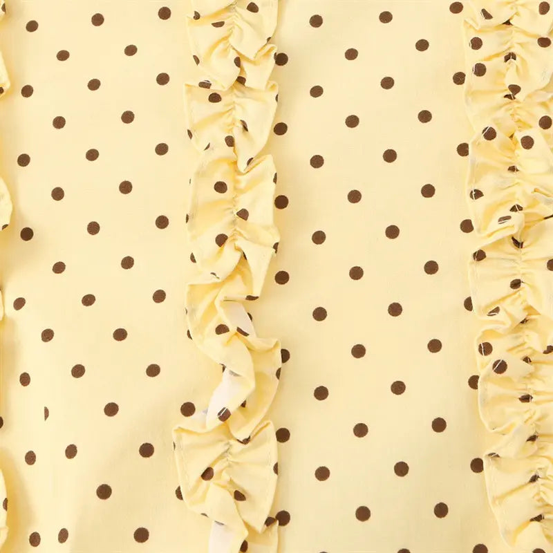 Macro closeup vertical layered ruffle placket on pale yellow brown polka dot cami, lightweight woven fabric texture