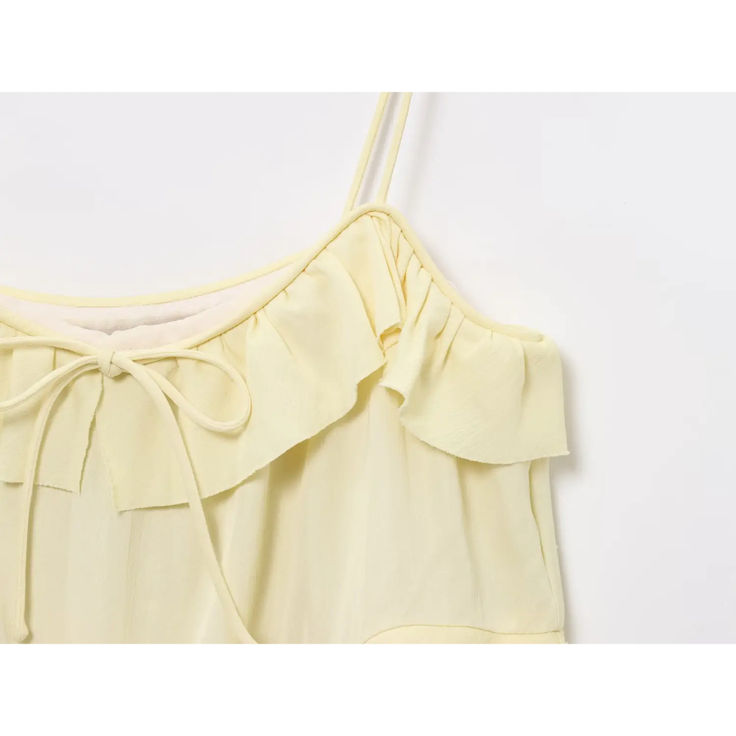 Close-up shot of self fabric tie bow on ruffle neckline of pale yellow cami mini dress