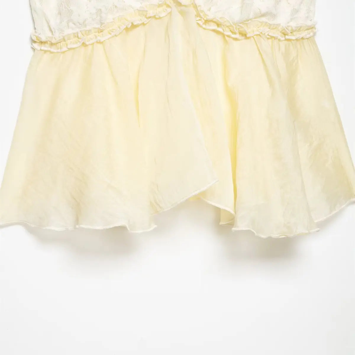 Hem detail of pale yellow ruffled camisole, showing the lightweight fabric and layered ruffle at the waist