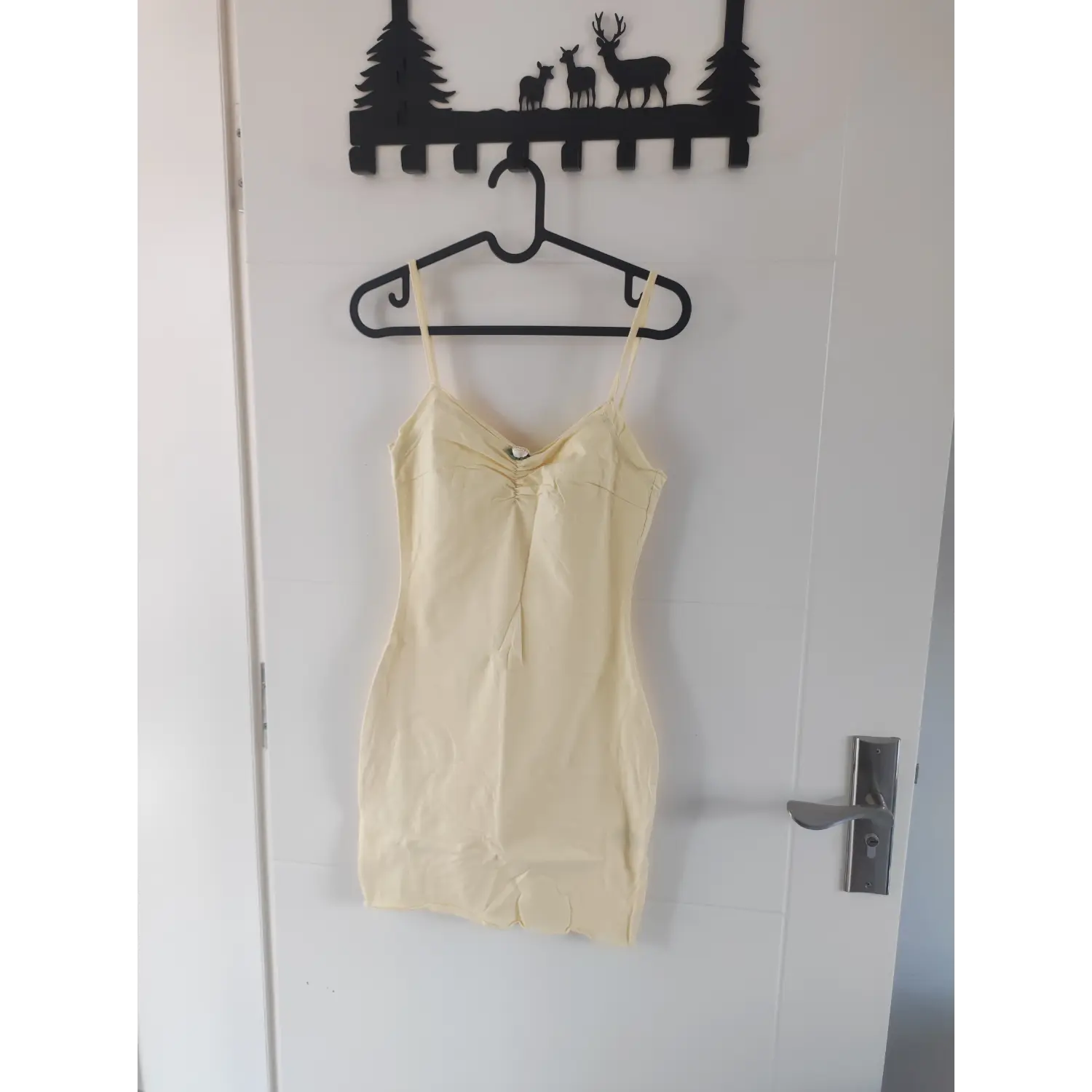 Pale yellow ruched bust spaghetti strap bodycon mini dress with small flower detail, front hanging view