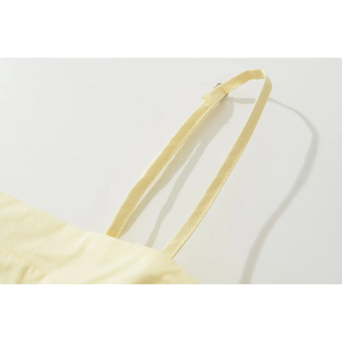 Close-up of the spaghetti strap, highlighting the adjustable slider and fine topstitching along the strap edge.