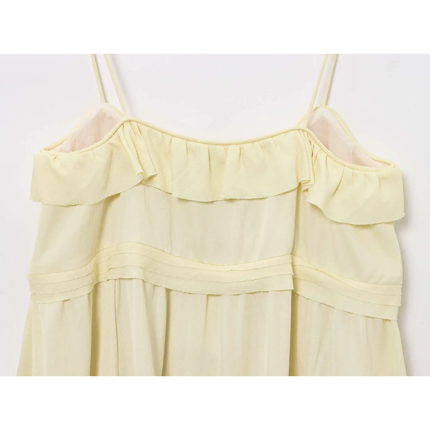 Close-up front view of pale yellow spaghetti strap mini dress with layered ruffle neck trim and horizontal waist bands