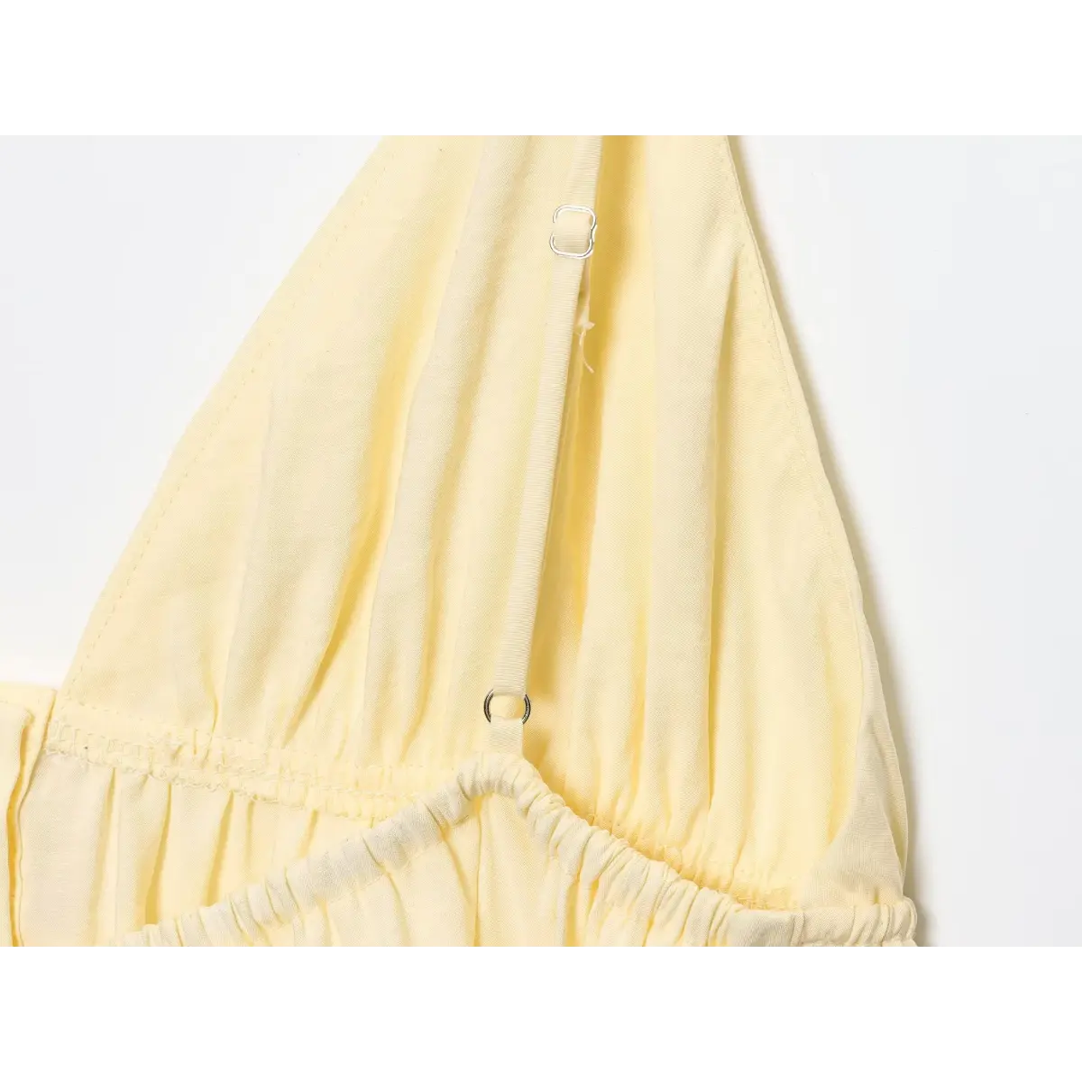 Close-up of the adjustable slider on the spaghetti strap of the pale yellow camisole.