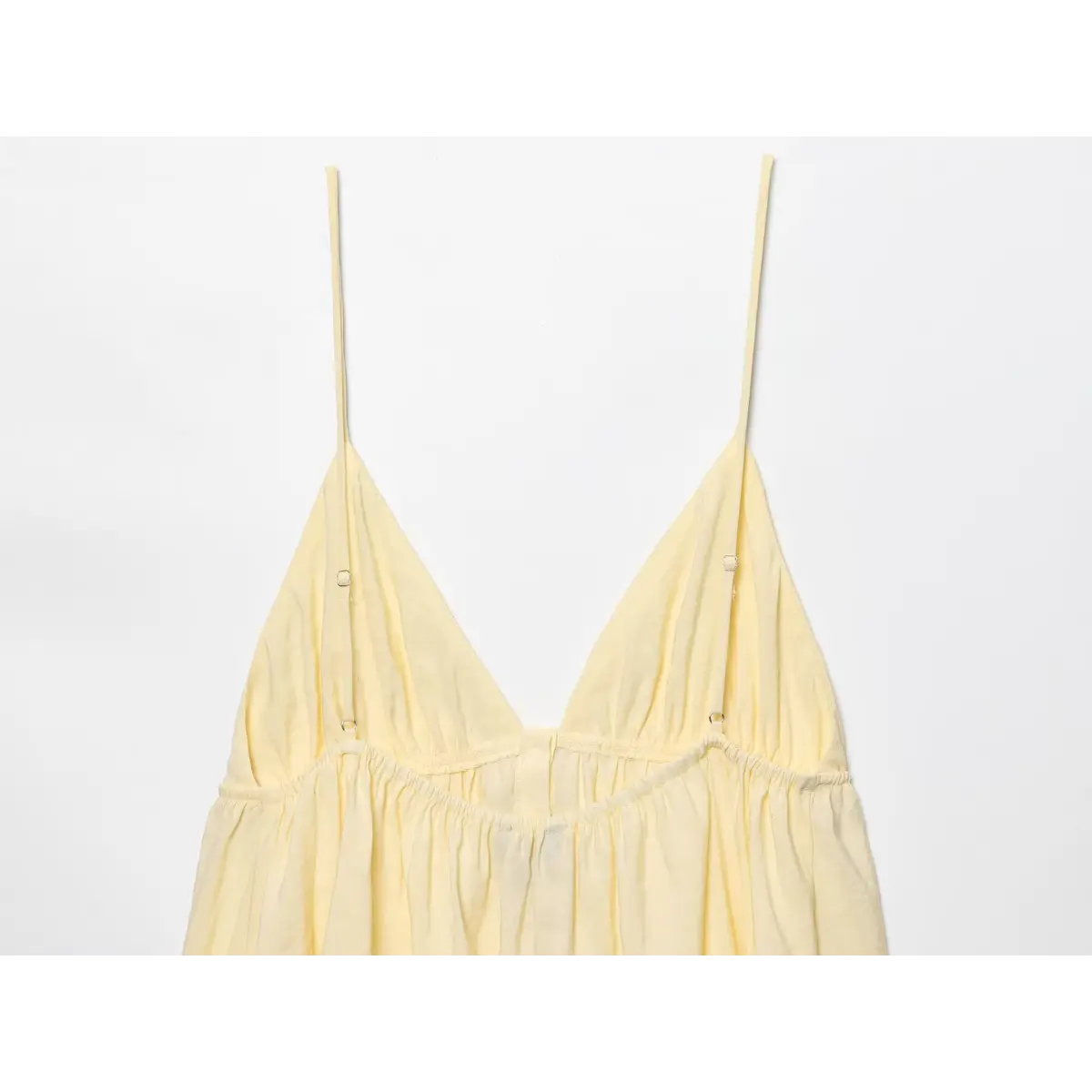 Full back view of the pale yellow camisole top, showing the deep V-neck and adjustable straps.