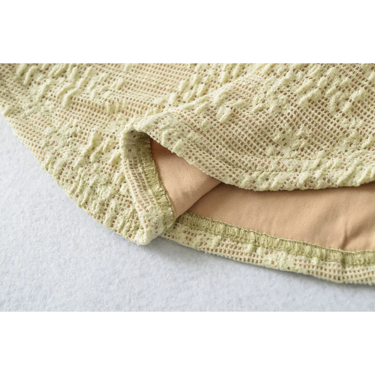 Close-up of the neatly stitched hem, showing the contrast between the lace exterior and nude lining.
