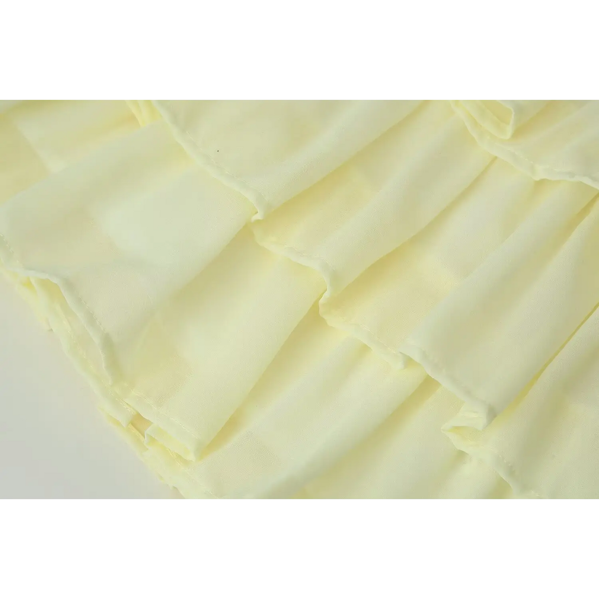 Close-up of pale yellow chiffon tiered ruffle skirt, showing soft layered fabric and neat finished seams
