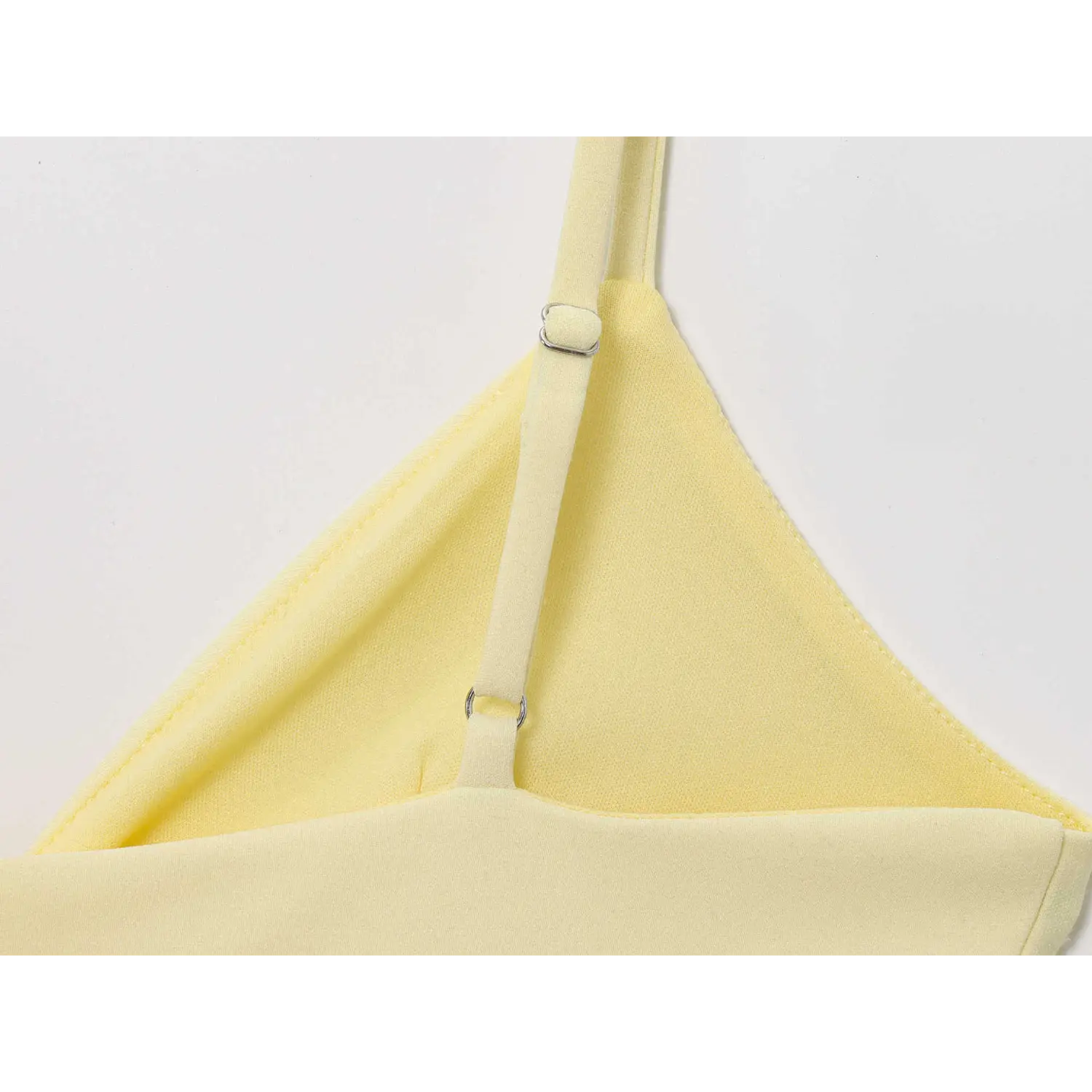Close-up of adjustable slider spaghetti strap on pale yellow deep V tulle peplum camisole top