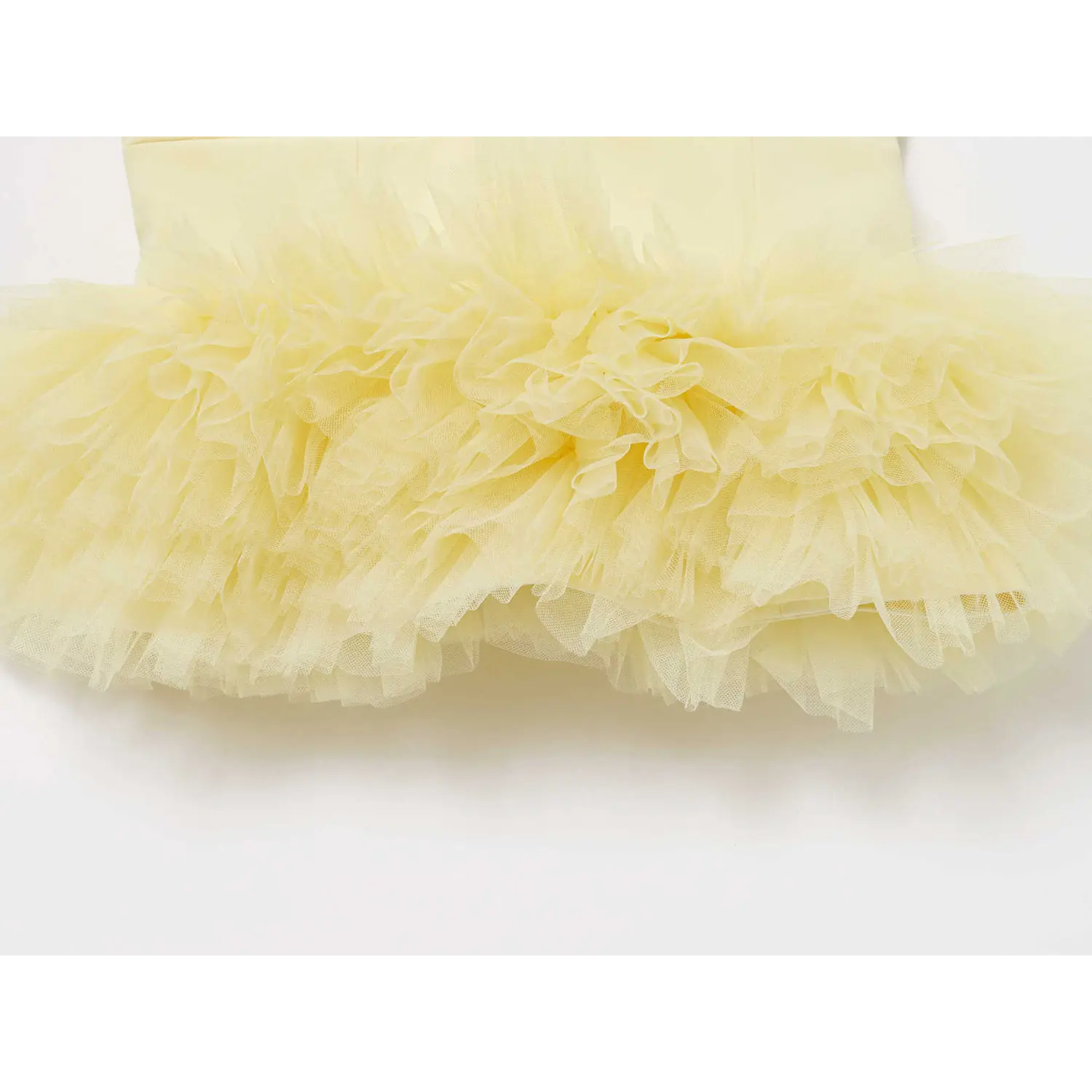 Partial shot of fluffy layered pale yellow tulle peplum skirt on camisole top