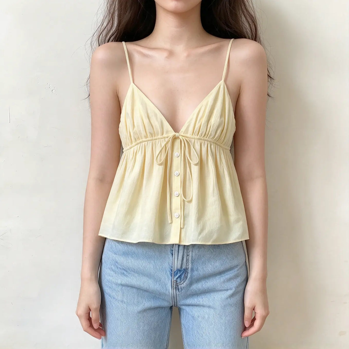Pale yellow v-neck cami top with thin spaghetti straps, front tie detail and button down flowy babydoll hem
