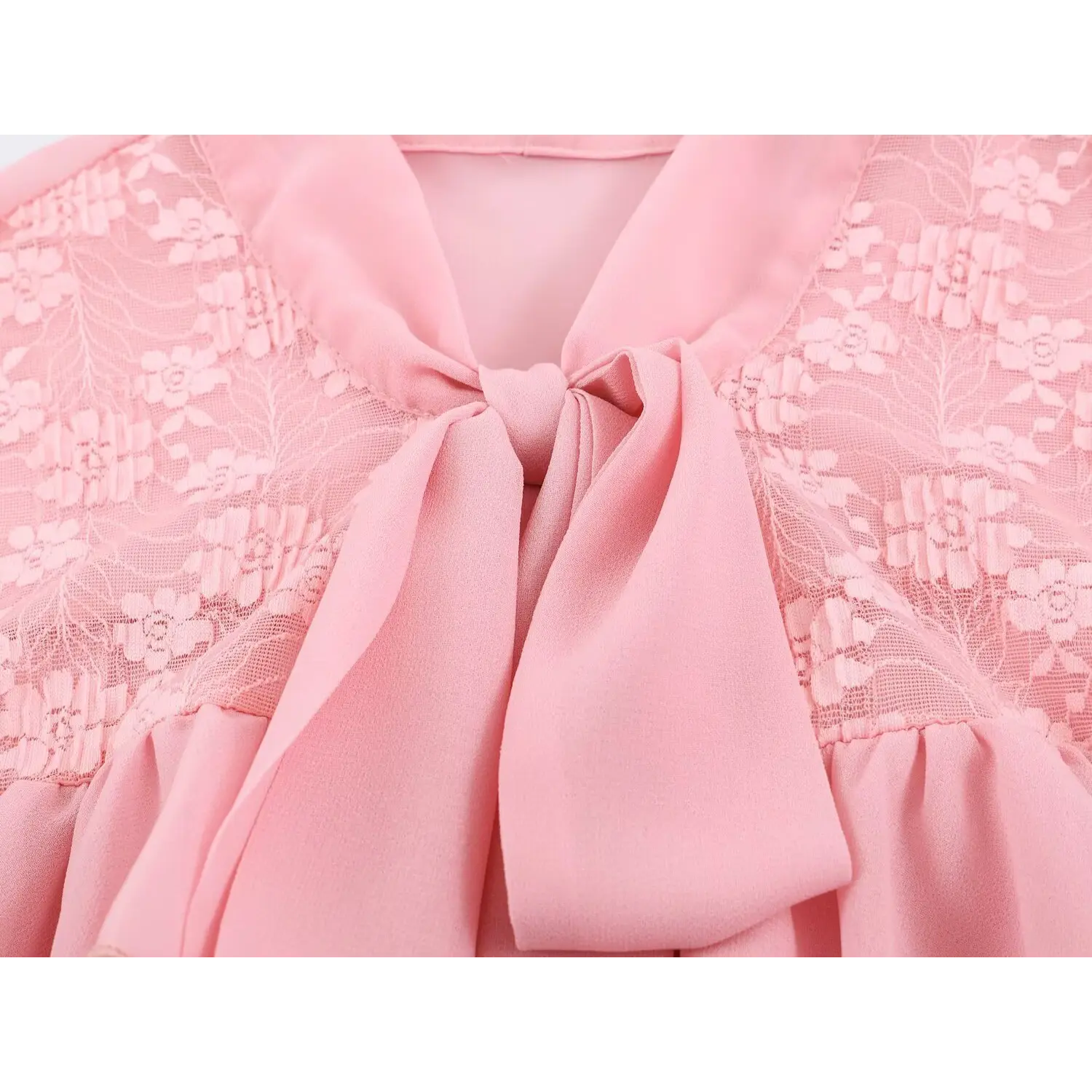 Closeup front neck self-fabric tie bow, floral lace yoke panel, pastel pink chiffon blouse detail