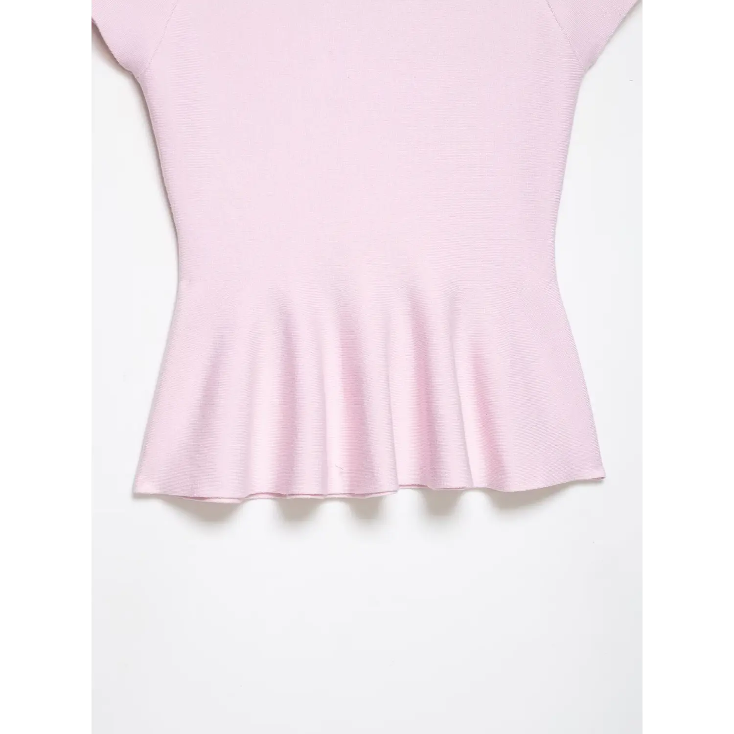 Front view of gathered peplum hem on pastel pink knit top