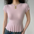 Lifestyle wearing shot of pastel pink fine rib knit peplum crewneck short sleeve top with flared hem, paired with denim jeans