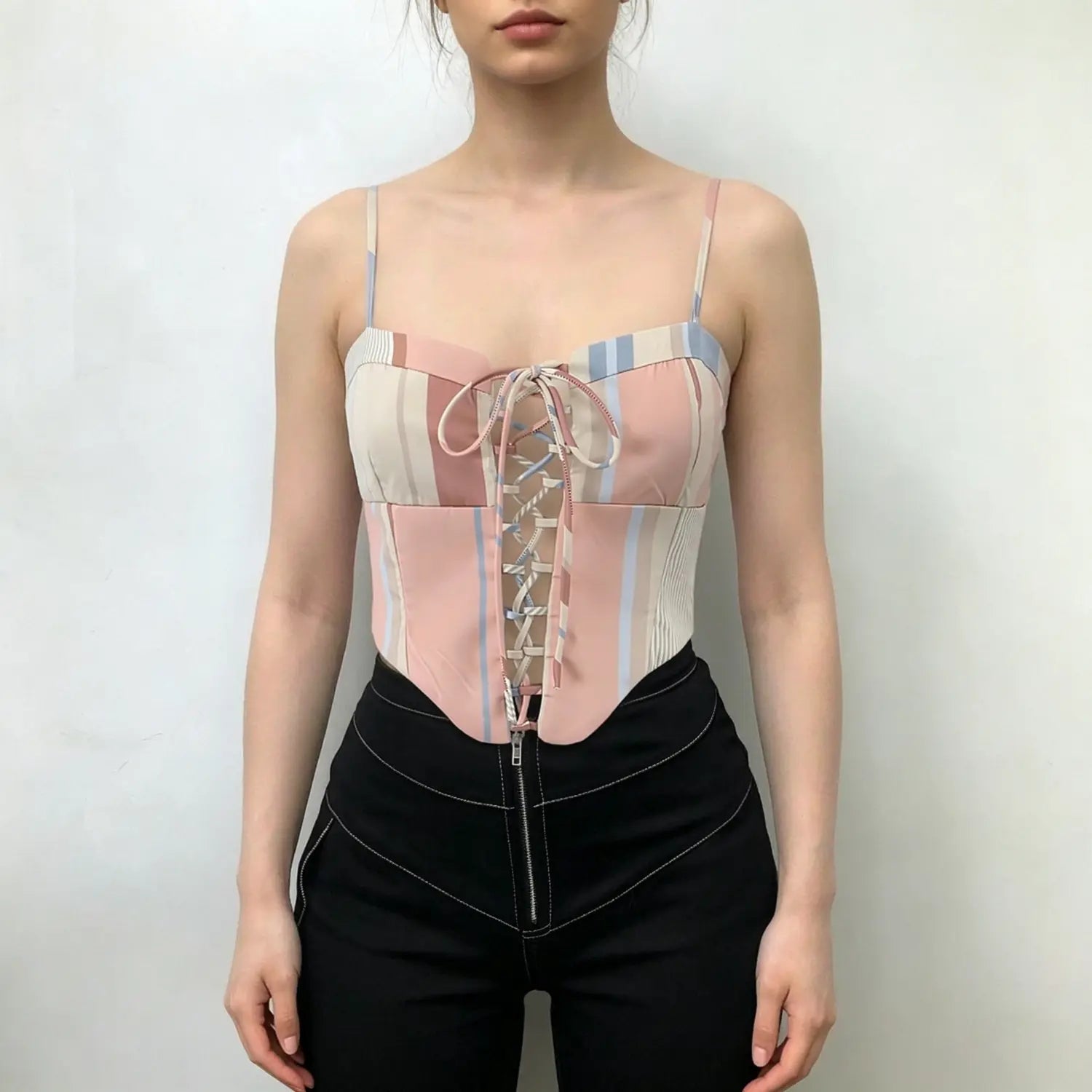 Model wearing pastel multi‑stripe corset cami top with front lace‑up detail, spaghetti straps