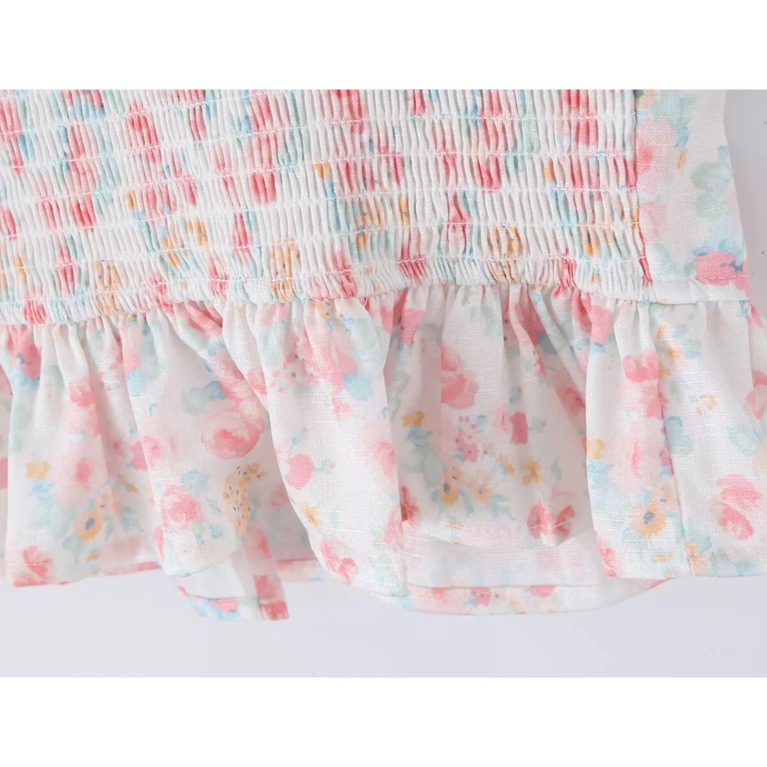 Front full flat lay cropped camisole top, white base pastel watercolor pink blue ditsy floral print, ruffled elastic cap sleeves edged with eyelet lace, deep V neck scalloped lace overlay, front matching fabric button placket, fitted waist flared peplum hem, full smocked elastic back panel