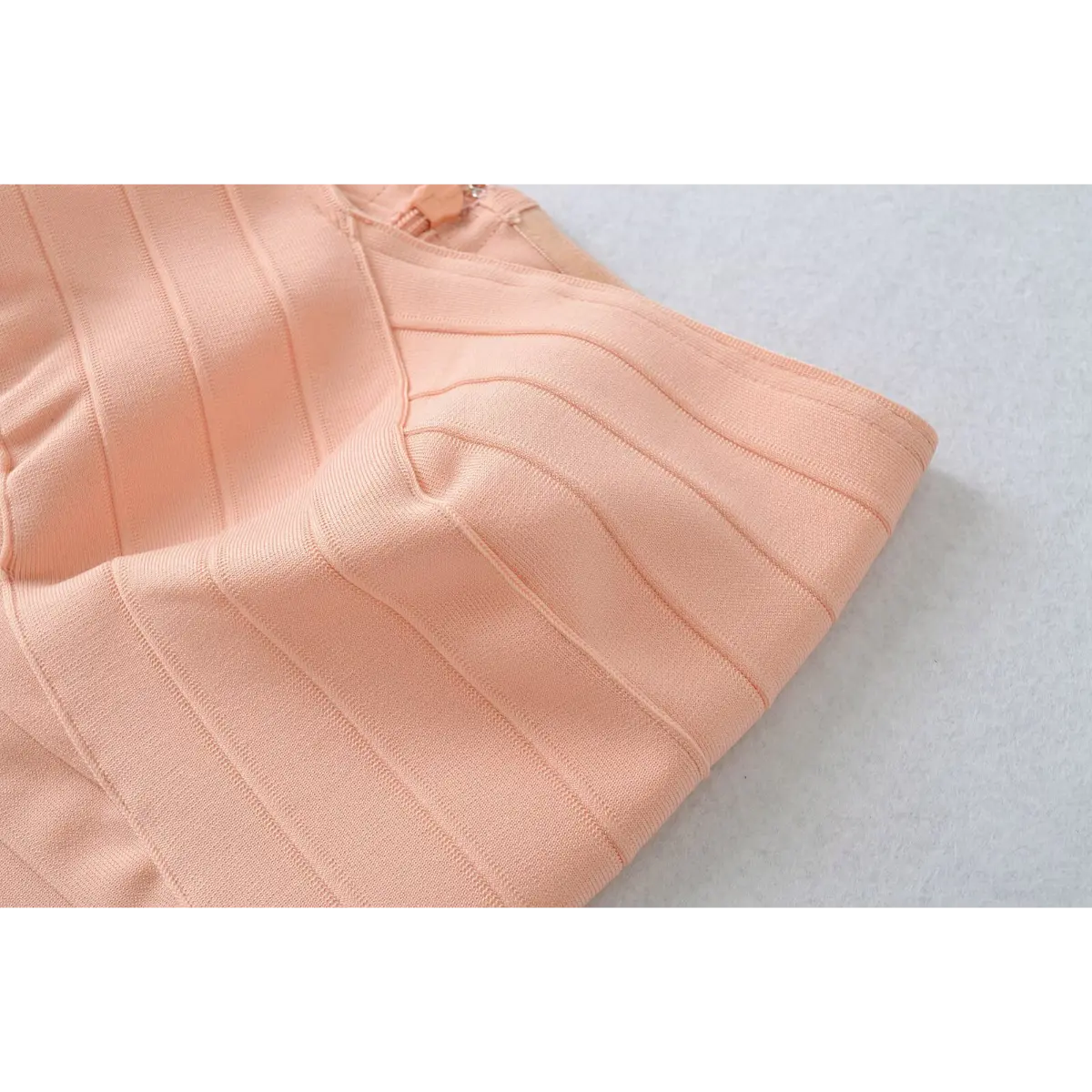 Close-up of the side zipper and structured bandage knit on the peach strapless top.