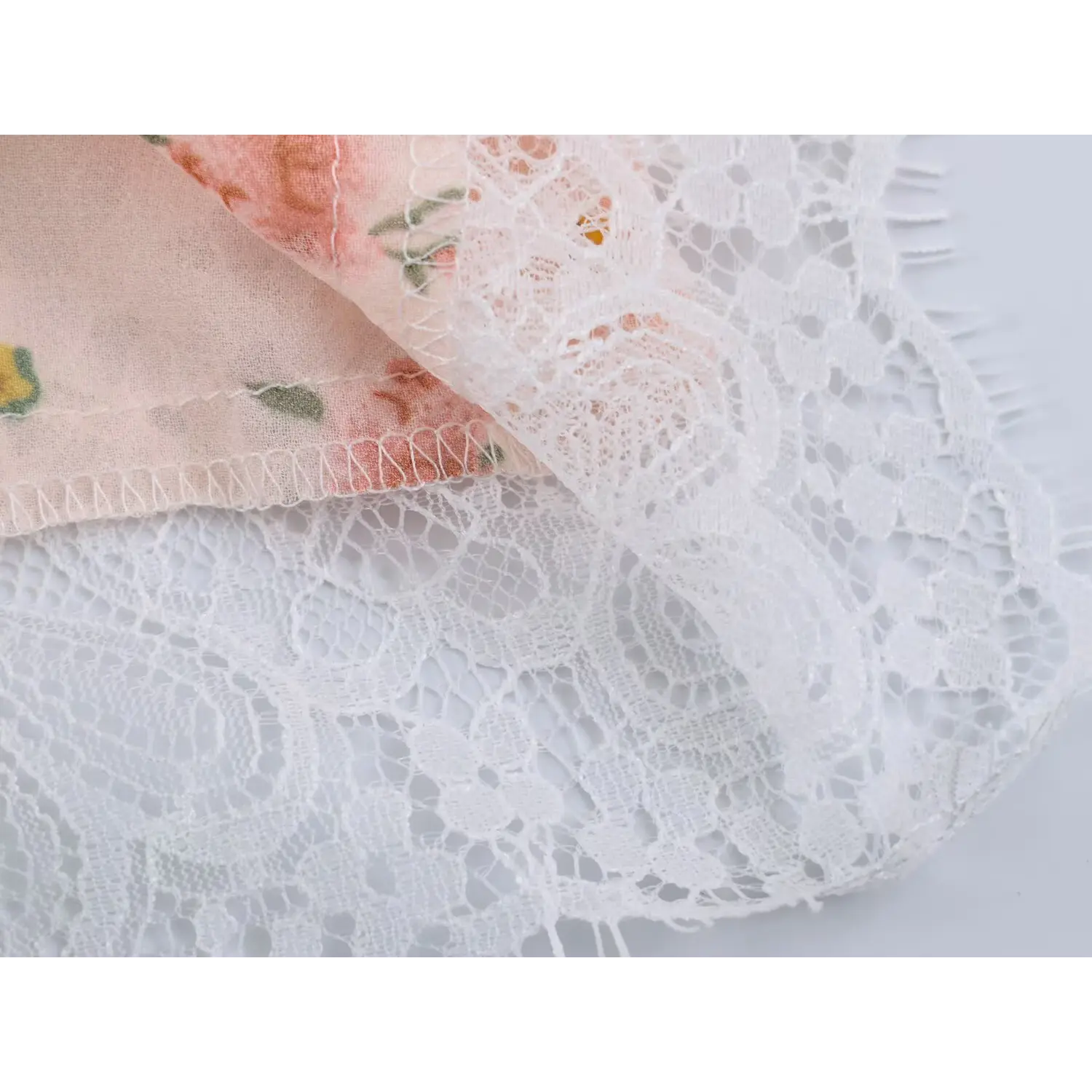 Folded hem shot showing dual lace layers, neat overlock stitching construction
