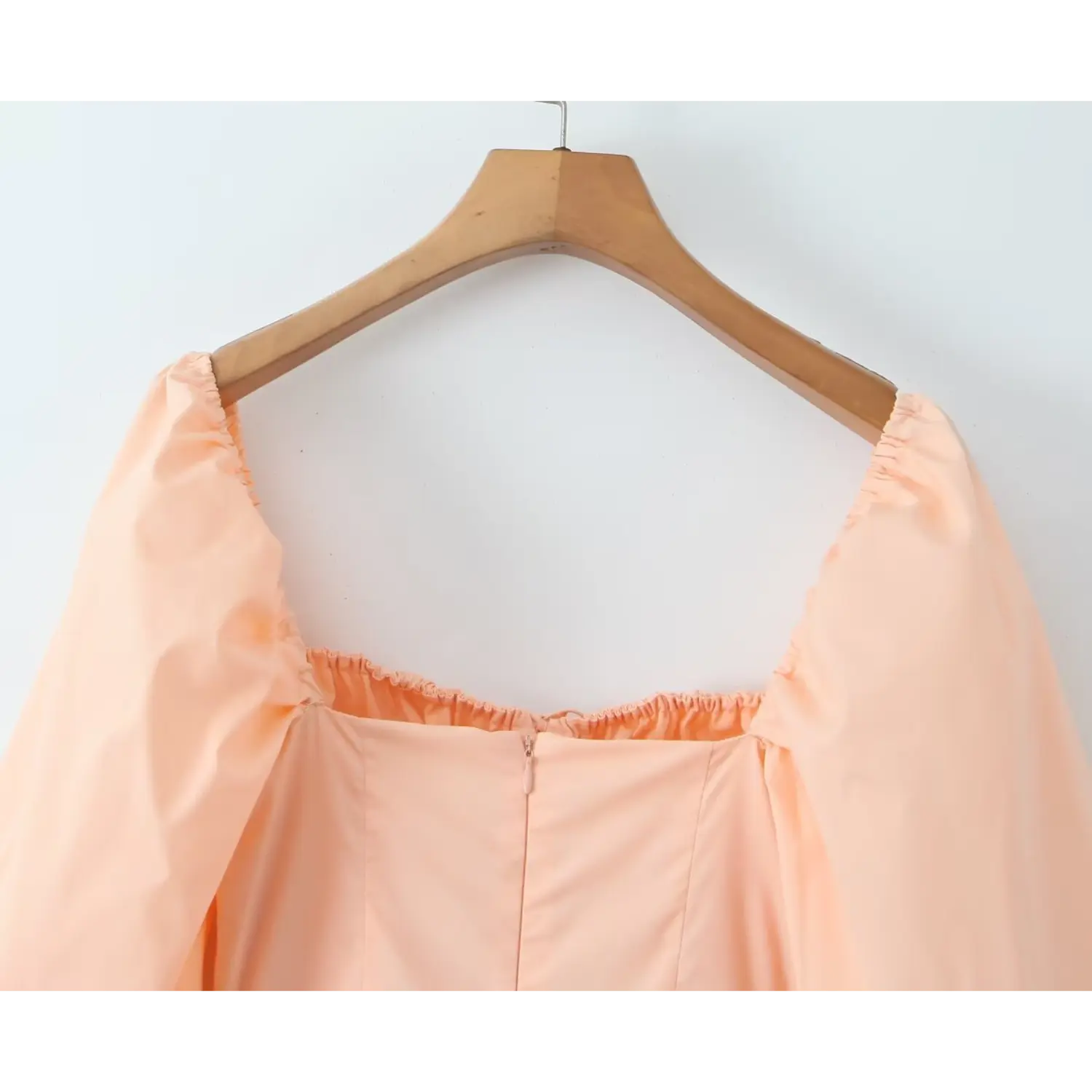 Close‑up back neck concealed zipper detail of peach square neck mini dress, elastic ruffle trim