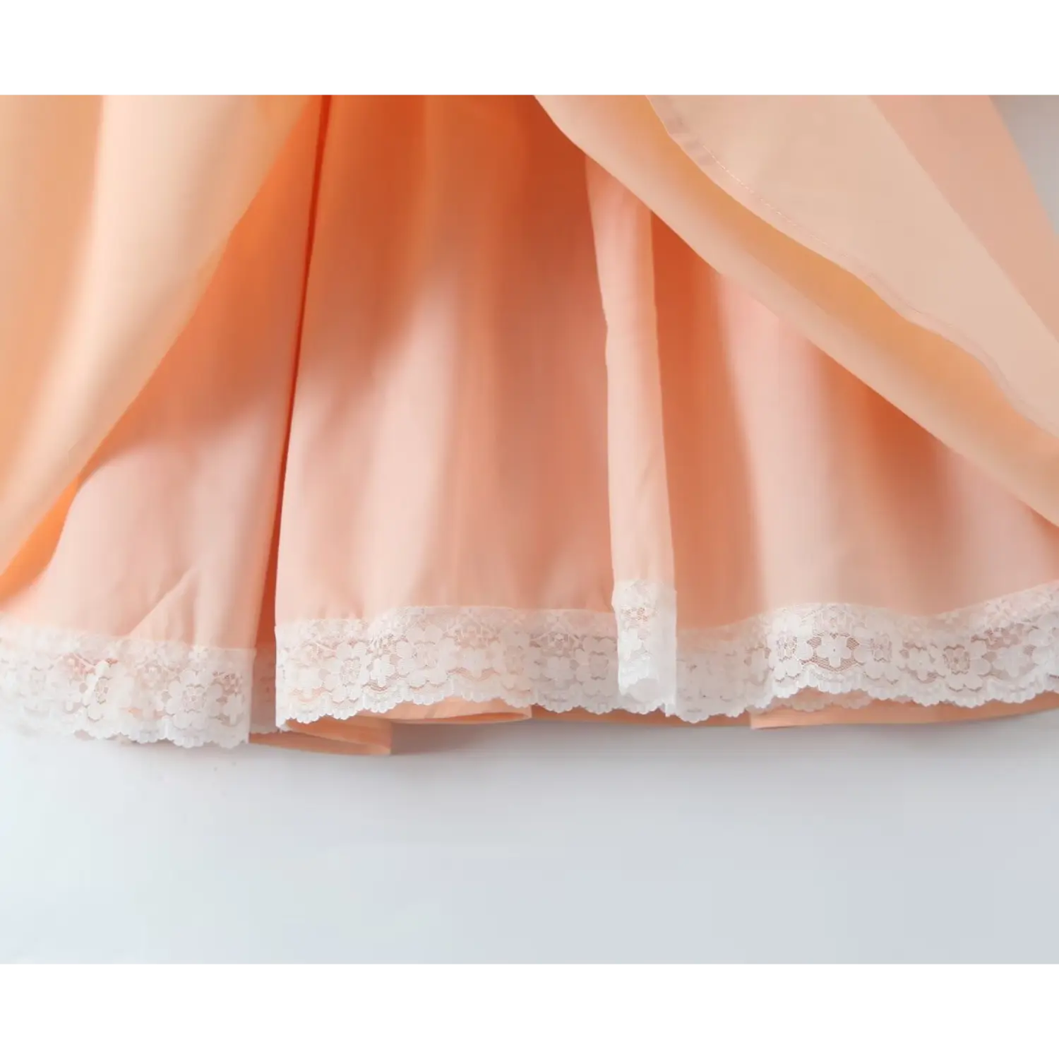 Inside view of peach dress skirt, white floral lace trim on inner lining hem
