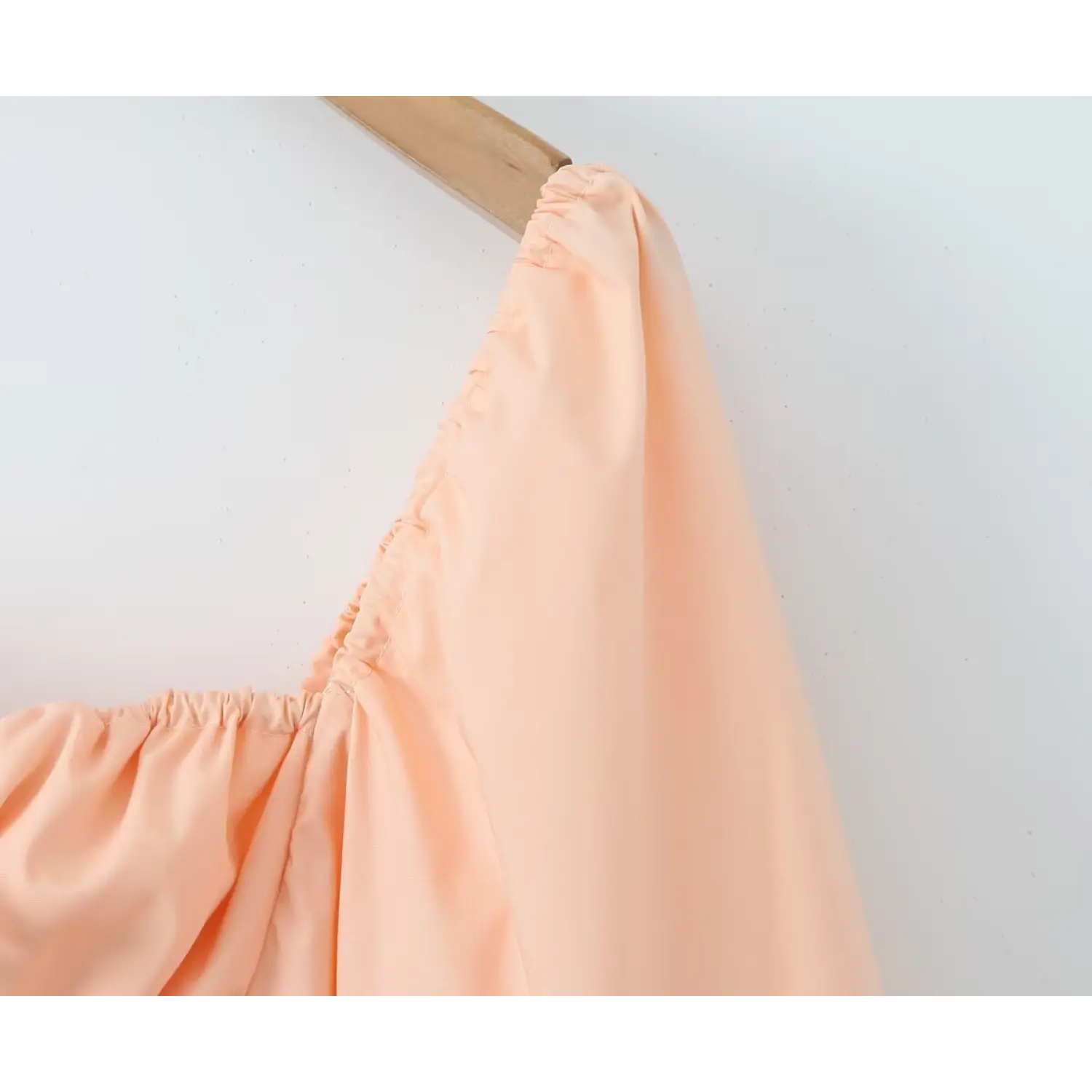 Close‑up shoulder elastic gathered detail of peach balloon puff sleeve dress, soft woven fabric texture