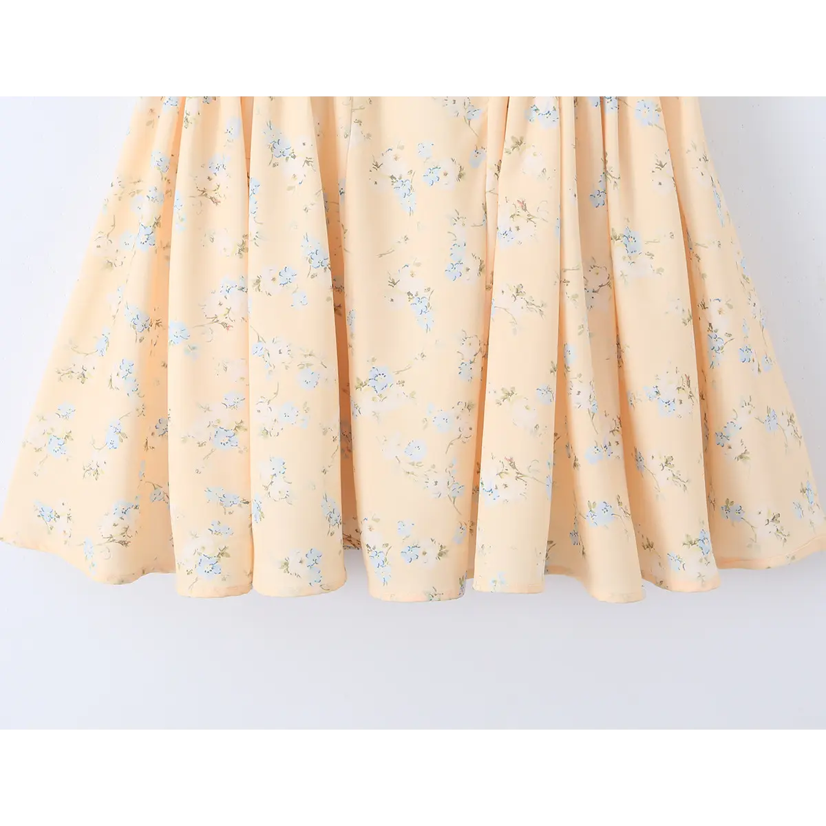 Close-up of the skirt hem and gathered fabric on a peach floral print dress.