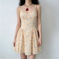 Full-body shot of a woman wearing a peach floral print spaghetti strap dress with a corset-style bodice.