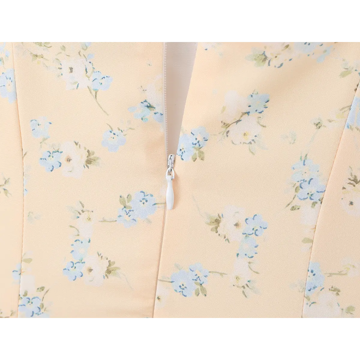  Close-up of the side zipper on a peach floral print dress.
