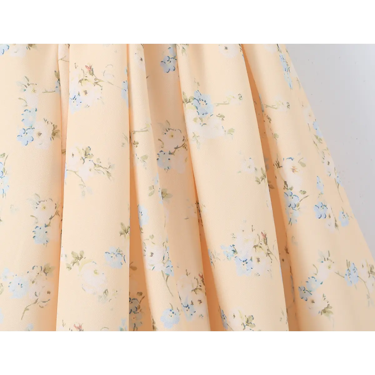 Close-up of the fabric drape and floral print on the skirt of a peach dress.